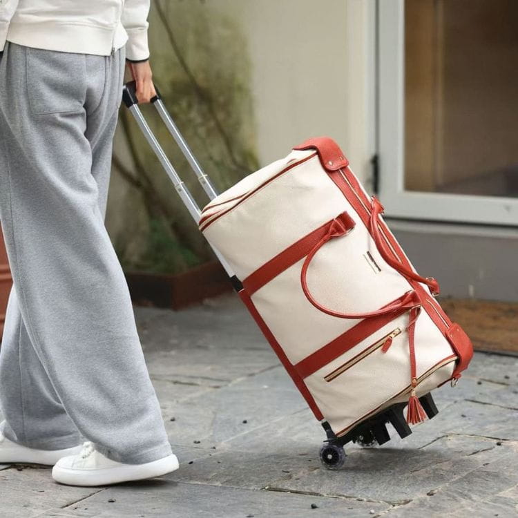 Sac de voyage beige tiré sur ses roulettes dans la rue