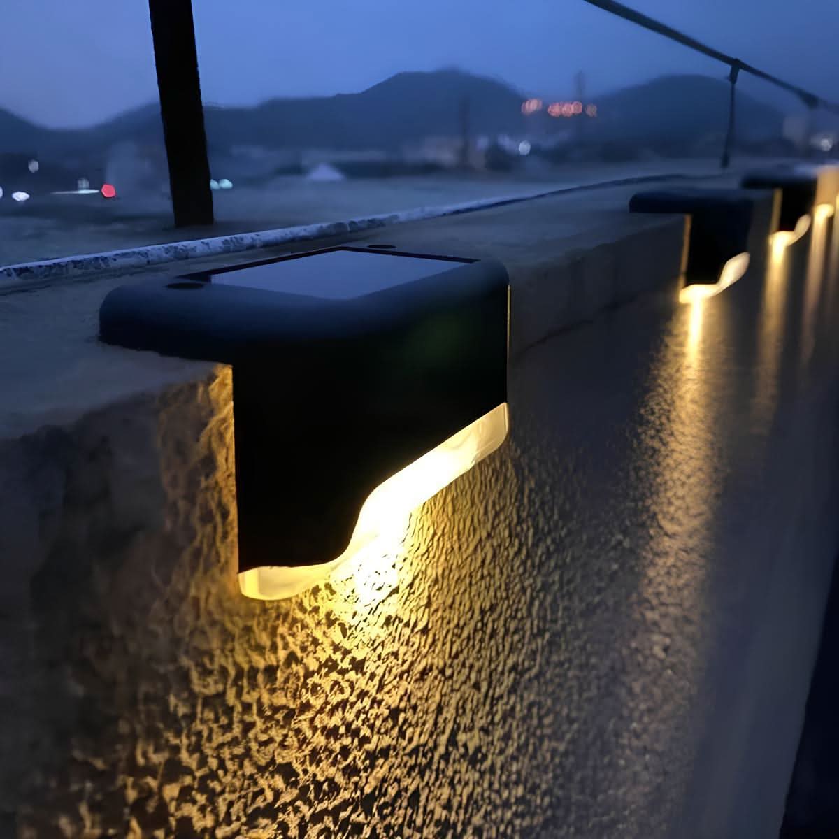 Lampes solaires allumées le long d'un muret à la tombée de la nuit