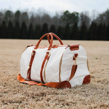 Sac de voyage beige posé dans un champ