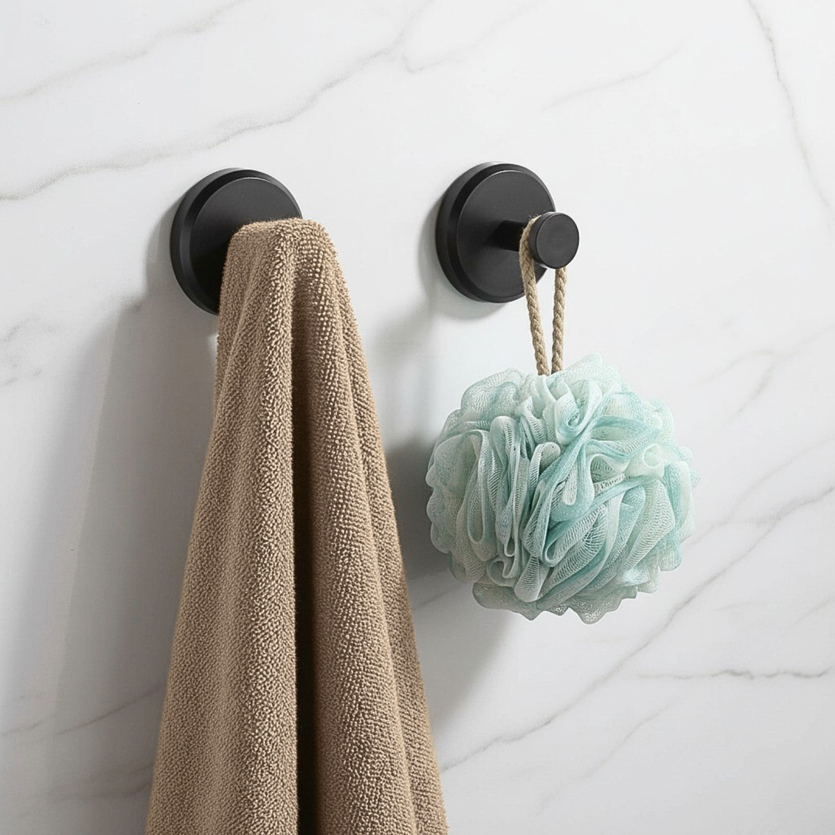 Deux patères à ventouse noires avec une serviette et une fleur de douche