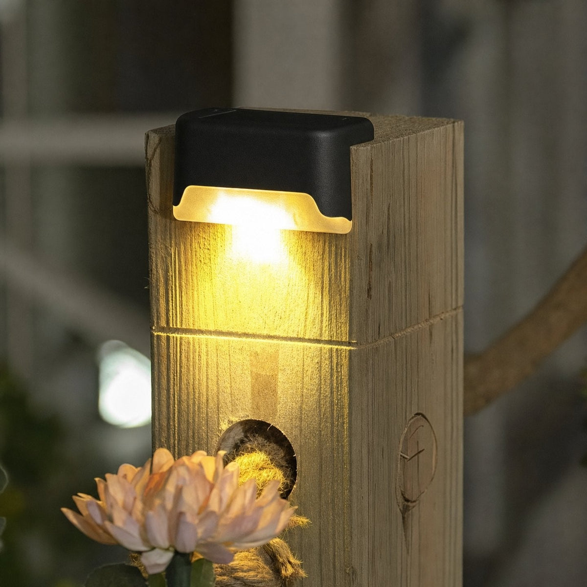Lampe solaire fixée en haut d'un poteau en bois, allumée le soir