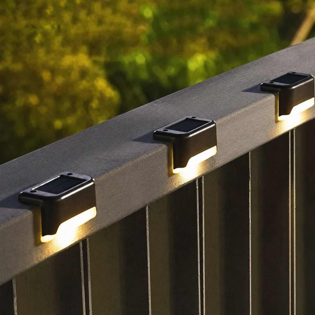 Trois lampes solaires allumées sur une rambarde de terrasse