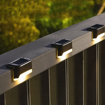 Trois lampes solaires allumées sur une rambarde de terrasse