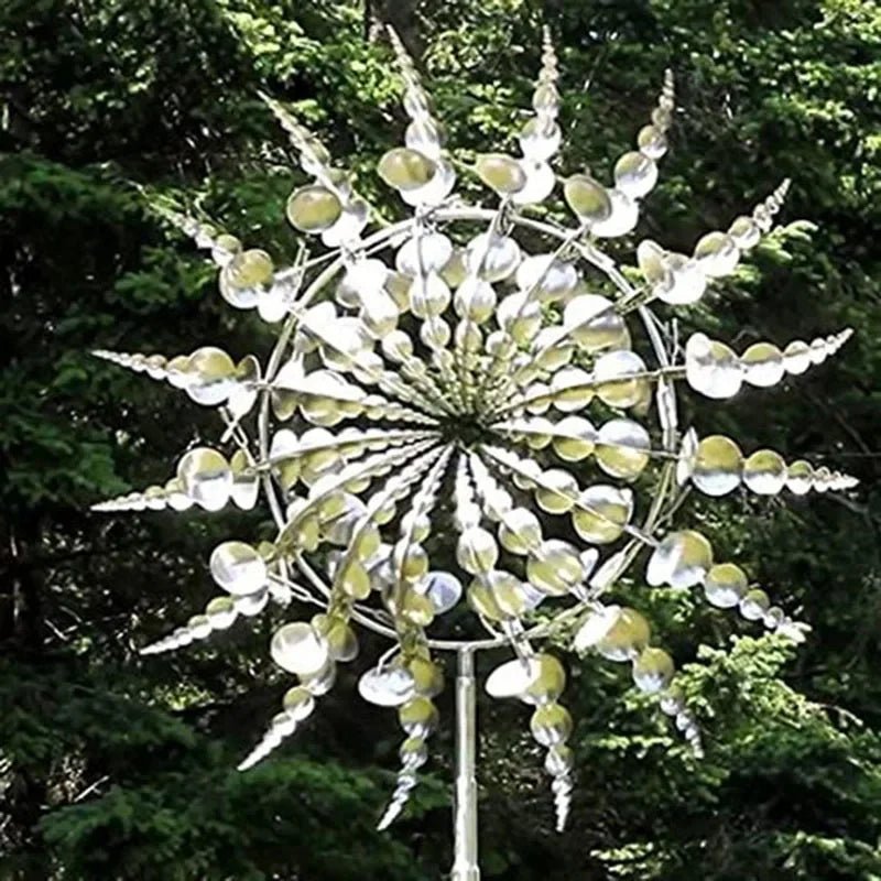 Moulin à vent cinétique Zéphyro en métal planté devant des sapins