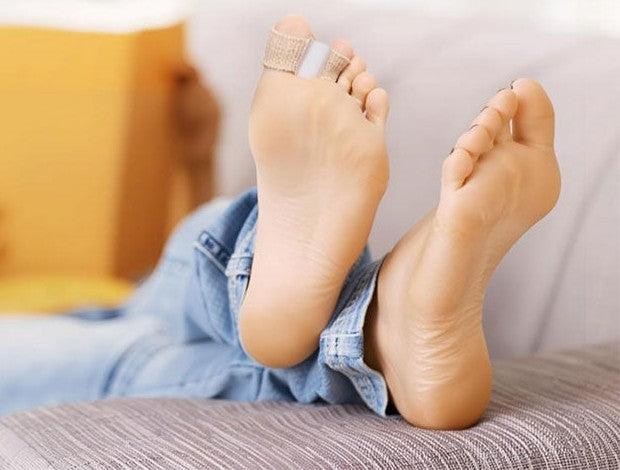 Pieds au repos sur un canapé avec le séparateur d'orteils Ortelle