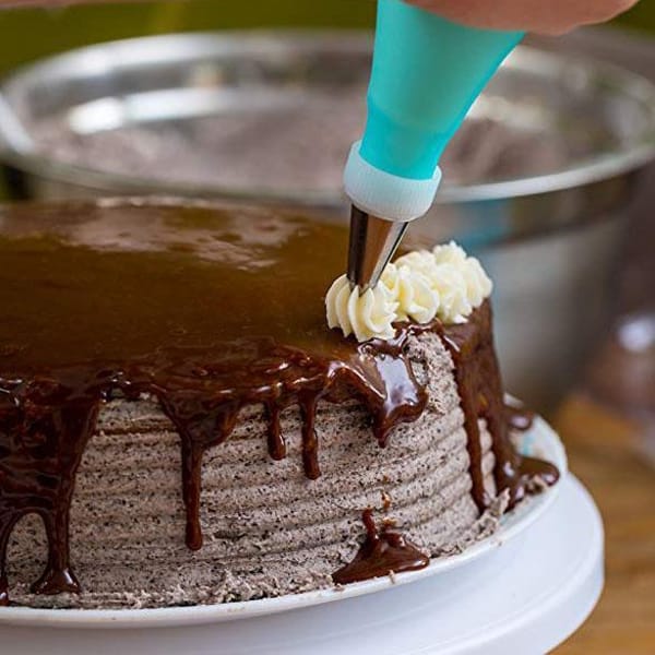 Poche à douille en train de décorer le haut d'un gâteau au chocolat